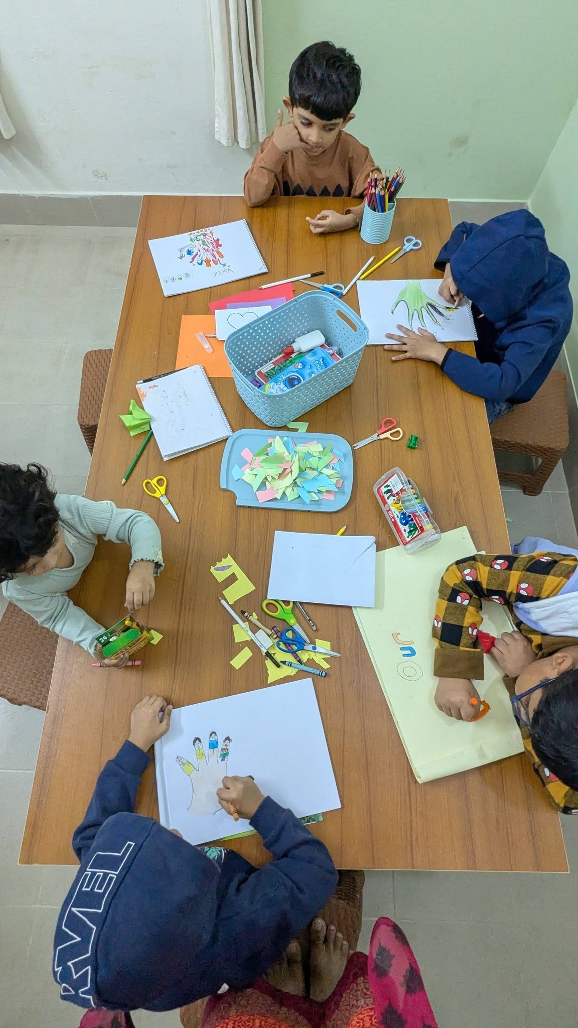 Owlets gathered around a craft table covered in scissors, colored paper and notebooks